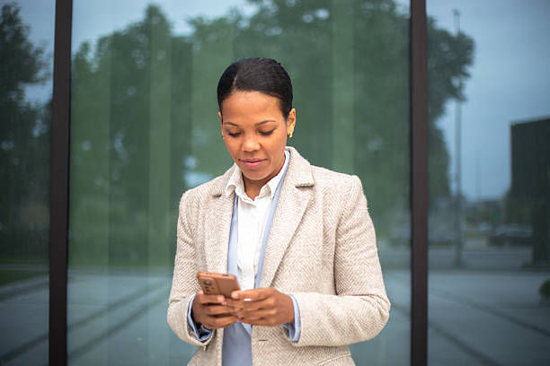 istock Businesswoman using smartphone in front of office building 2219998806