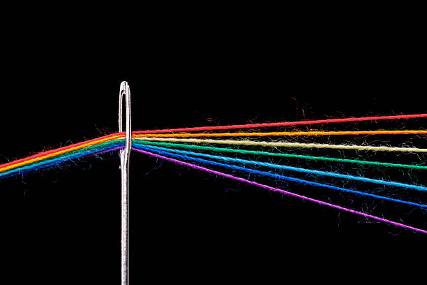 istock multi-colored threads for sewing in the form of a rainbow pass through an antique needle on a black background 2219999169