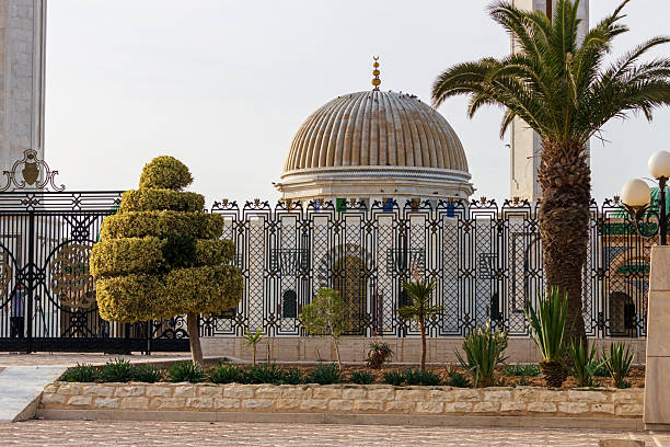 istock a building with a prominent dome, possibly a mosque or cultural site, partially obscured by trees and a fence. 2219999996