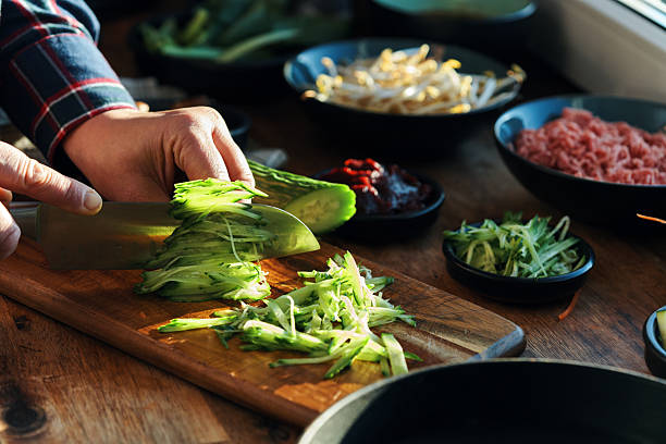 istock Cutting Cucumber for Preparing Bibimbap Korean Rice Dish in Domestic Kitchen 2220004096