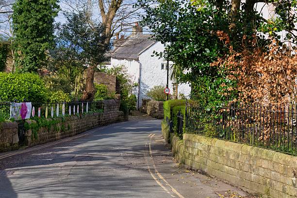 istock A quiet road is lined with greenery and stone walls, leading towards a white building in the distance. 2220006119