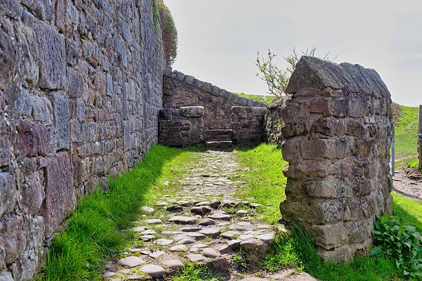 istock A stone pathway leads through an opening in ancient stone walls. 2220006320