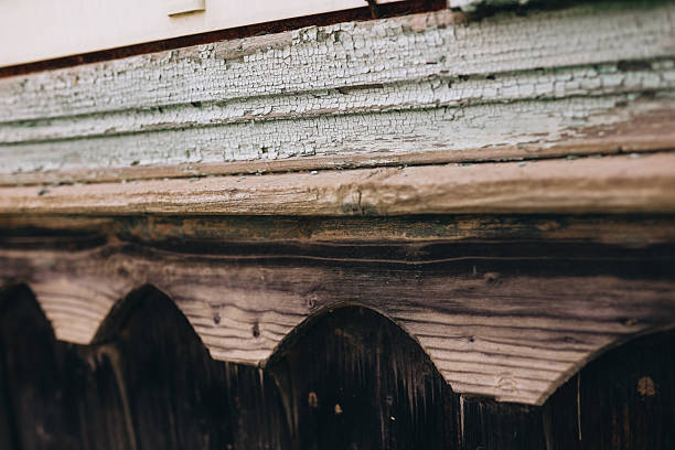 A close-up of an old wooden facade with decorative elements and peeling paint. The image captures the texture of weathered wood and the nostalgic feel of traditional rustic architecture.