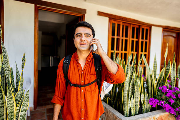 istock Young traveler man talking on phone in front of hotel 2220009452