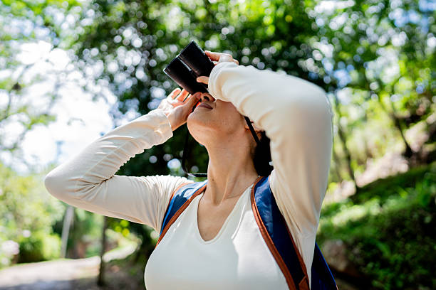 istock Young traveler woman using binoculars at public park 2220009491