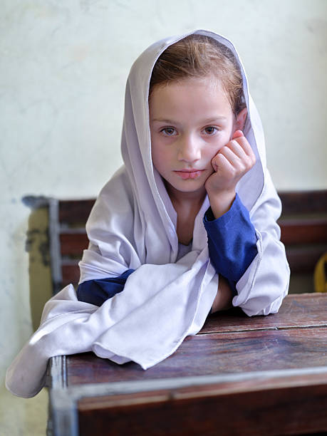 Elementary age student leaning on desk looking pensive in religious garment