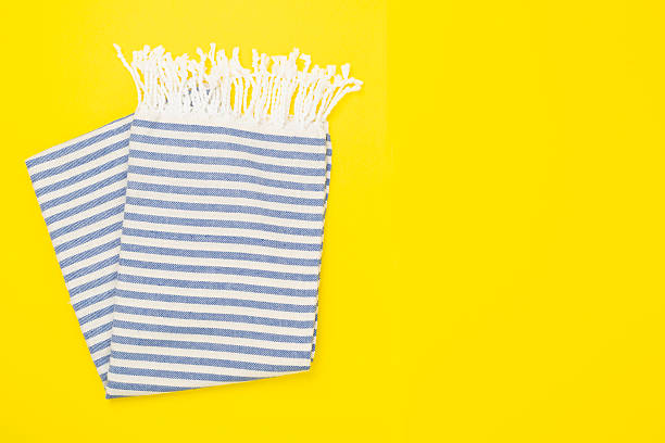 Flat lay with a pink mesh bag, dark sunglasses, and SPF cream on a beach towel on the sand.