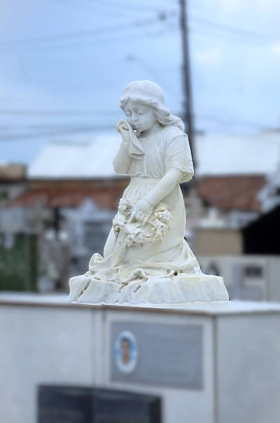 A statue of a crying girl decorating a grave in a cemetery