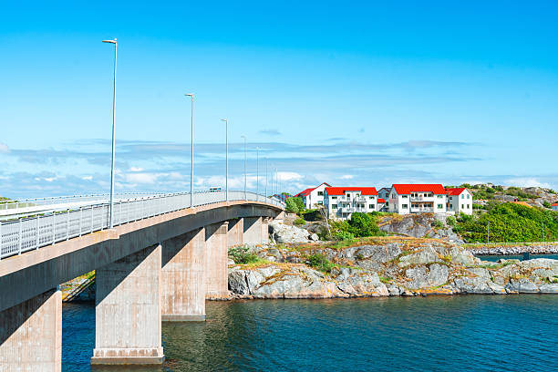 Seascape on the Resö island in the Bohuslän province showing a typical red painted boathouse on the rocky coast with a wooden pier under a stormy sky on a sunny summer day.