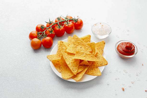 istock Plate of nacho chips with tomatoes, salt and dip on white background 2220025273