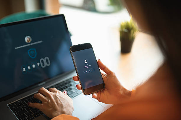 istock Asian woman authorizing her identity by entering code from her phone to log in to her laptop. 2220025402