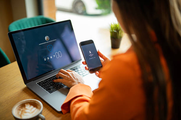 istock Asian woman authorizing her identity by entering code from her phone to log in to her laptop. 2220025425