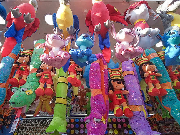 Frontal view of a tightly packed carnival booth filled with colorful plush toys hanging in vertical rows.
