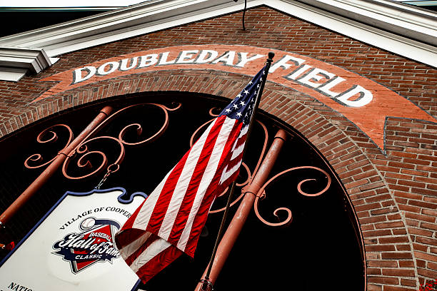 Doubleday Field, Cooperstown, New York, main front entrance, two American flags, overcast sky, historic baseball field owned and operated by the village of Cooperstown.  Photo date: August 5, 2018.