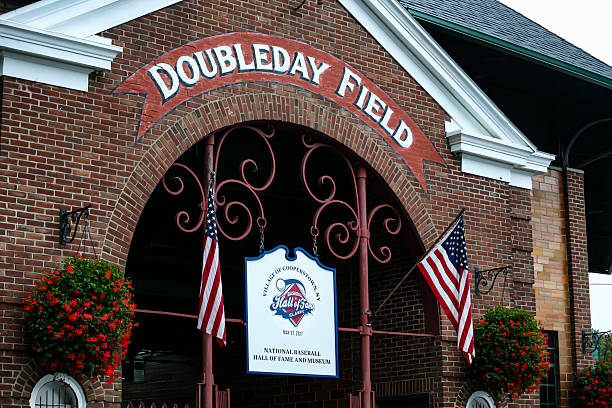 Doubleday Field, Cooperstown, New York, main front entrance, two American flags, overcast sky, historic baseball field owned and operated by the village of Cooperstown.  Photo date: August 16, 2017