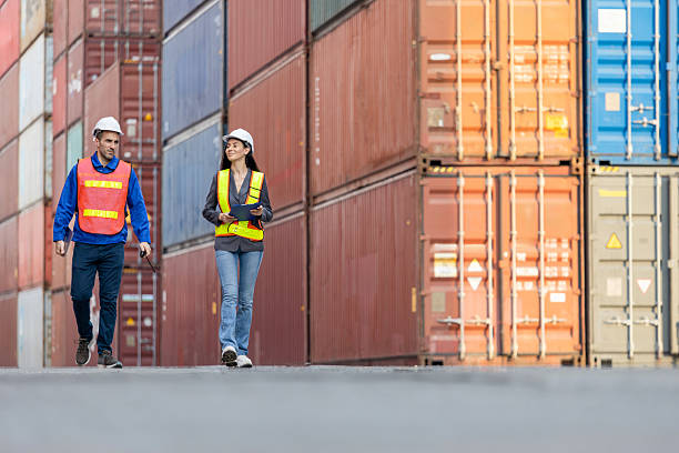 istock Logistics Team Inspecting Shipping Containers at Port, Industrial Workers Walking Through Cargo Terminal, Engineers at Container Yard 2220044348