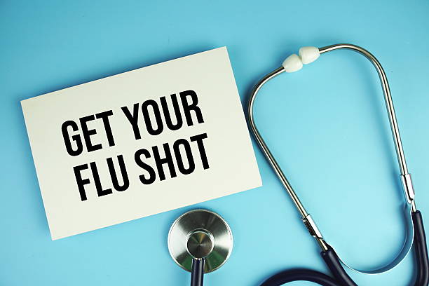 istock Get Your Flu Shot text on paper card with stethoscope top view on blue background 2220046590