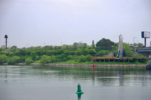 Incheon, South Korea - May 19th 2025: Duri Ecological Park lines the Ara Waterway with its greenery and observation deck, marked by a colorful tower sculpture near the canal's edge.