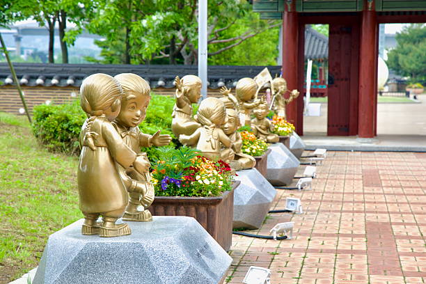 Incheon, South Korea - May 19th 2025: A row of playful bronze statues depicting children in traditional dress stands beside flower planters just outside Suhyangwon's hanok gate, adding a whimsical charm to the cultural plaza.