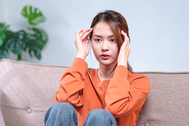 istock A thoughtful young woman seated on a sofa, resting her head on her hand, appearing deep in contemplation 2220056563