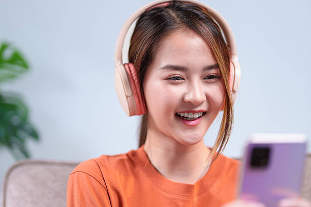 istock A young woman wearing headphones, smiling while using her smartphone, immersed in an engaging mobile experience 2220056590