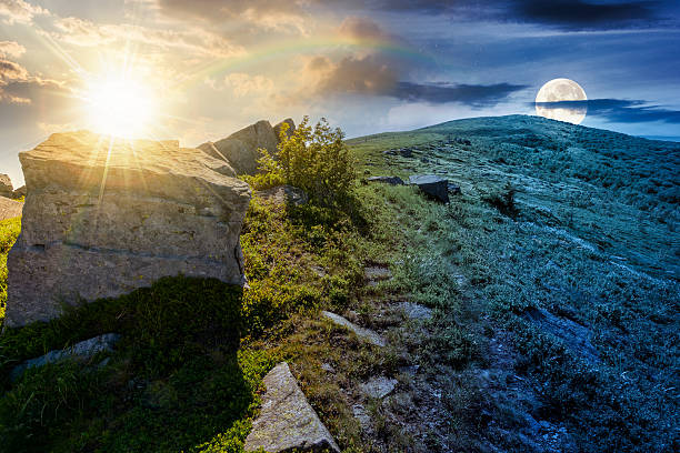 boulder on a hill under blue sky with clouds in summer stock photo