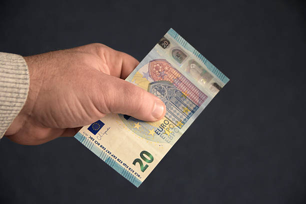 istock A hand holding on a black background a twenty euro bill 2220070779