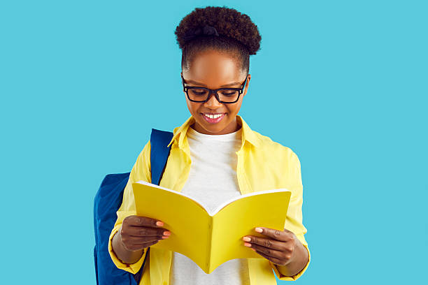 istock Happy young African American woman student with backpack, holding yellow notebook standing in studio 2220071961