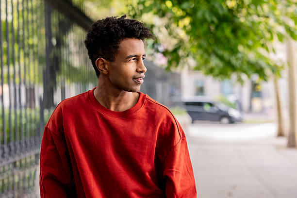 Young man wearing red sweatshirt looking away in the city