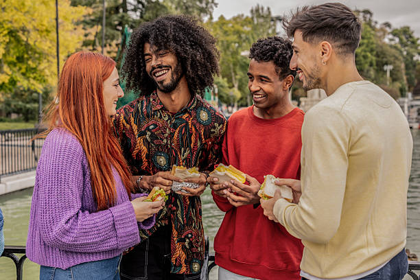 istock Cheerful friends enjoying sandwiches by the river 2220072893