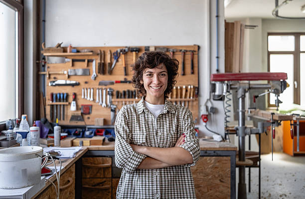 istock Smiling Female Carpenter in Bright Workshop Surrounded by Tools and Wooden Projects 2220074127
