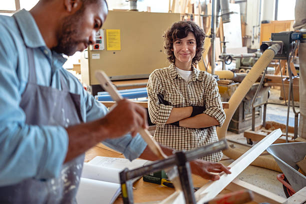 istock Female And Male Carpenters Working Together In Bright Indoor Workshop Setting 2220074442