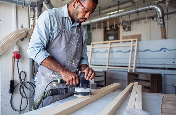 istock Focused Mid Adult Male Carpenter Sanding Wood in a Bright Workshop 2220074462