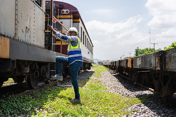 Railway Engineer Inspecting Train Car on Tracks, Railroad Worker in Safety Vest Climbing onto Freight Train, Technician Conducting Pre-Departure Check on Train