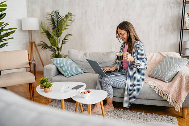 istock Young Woman Working On A Laptop And Drinking Coffee While Sitting On The Sofa At Home 2220074869