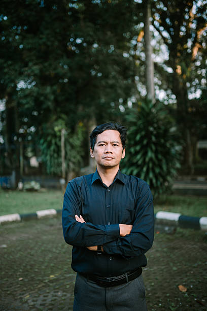 istock Confident Asian Man with Crossed Arms Posing in Outdoor Setting 2220075548
