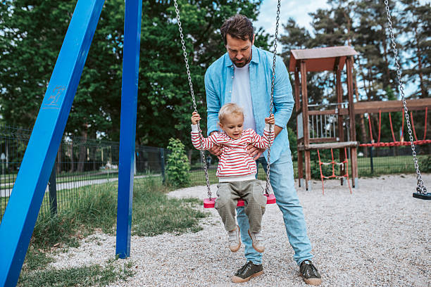 istock Father swinging small son on playground swing. 2220076148