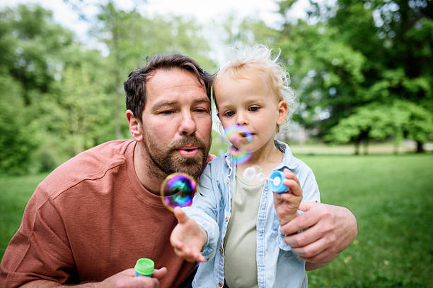 istock Father and son blowing soap bubbles in park. 2220076193