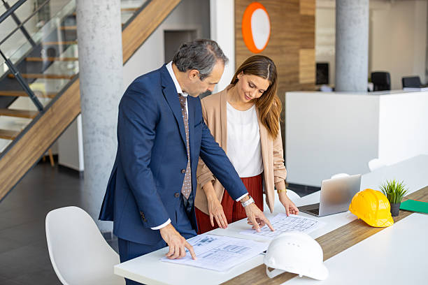 istock Two architects examining blueprints in a contemporary office, discussing project details 2220077795