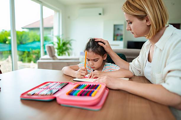 istock Mother helping her young daughter with homework at home 2220079598