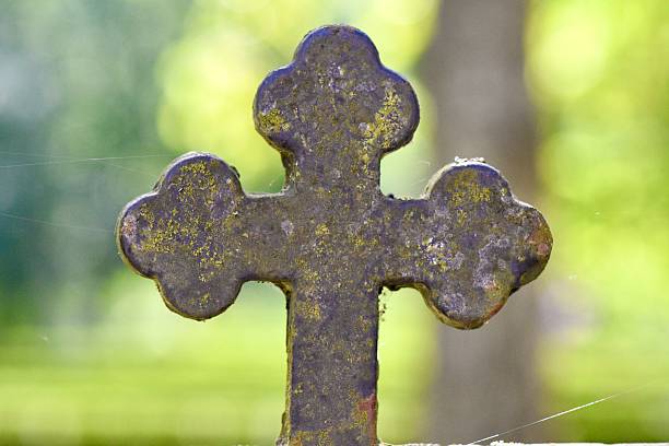 In an Irish cemetery, an ancient stone cross stands, weathered by time yet steadfast in its presence. Carved with intricate detail, it bears the weight of history and reverence. At its center, a solemn depiction of the sacred heart radiating with eternal love and compassion, serves as a poignant reminder of faith and remembrance.
