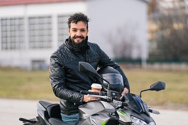 istock Man in leather jacket with coffee enjoying a motorcycle ride in a sunny outdoor setting. 2220083812