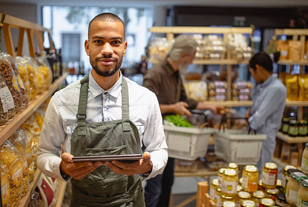 istock Confident Multiracial Grocery Worker Using Digital Tablet in Brightly Lit Store 2220085588