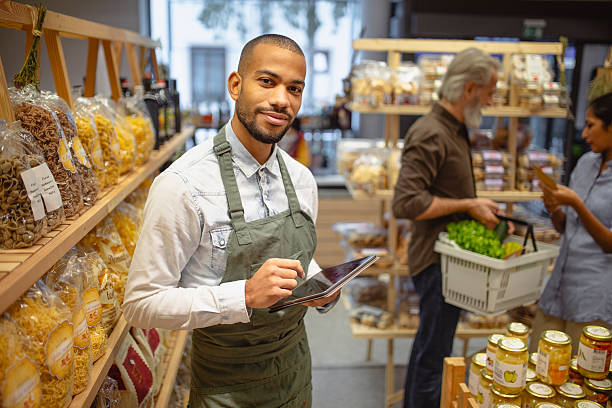 istock Confident Multiracial Male Grocery Worker Using Digital Tablet in Organic Food Store 2220085603