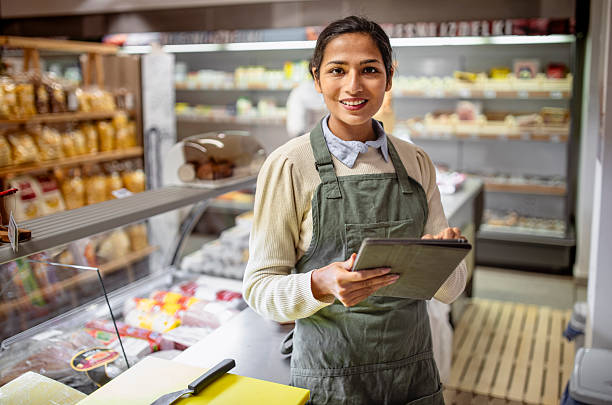 istock Cheerful Young Female Grocery Store Worker Using Digital Tablet In Modern Bakery Department 2220085631