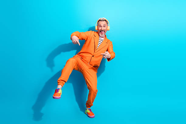istock Middle aged man wearing an orange suit making gestures against a blue background, showing cheerfulness 2220087057