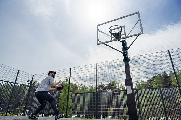 istock Man Practicing Basketball on Outdoor Court Under a Bright Sky 2220087911
