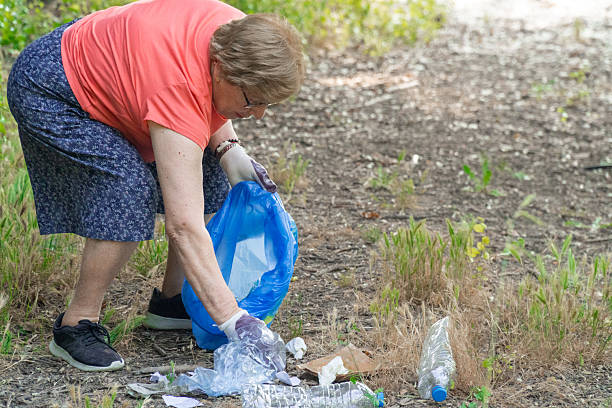 istock Senior volunteer cleaning a forest, putting plastics and garbage into a bag 2220090297