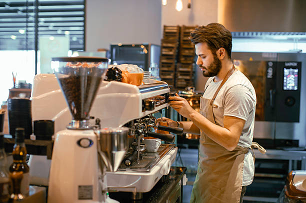 istock Young Male Barista Focused on Preparing Fresh Espresso Using a Professional Machine in a Trendy Coffee Shop 2220093045