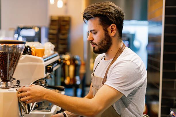istock Young Male Barista Focused on Preparing Fresh Espresso Using a Professional Machine in a Trendy Coffee Shop 2220093060